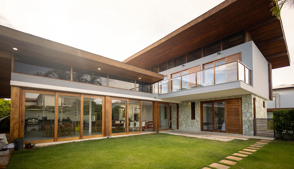 Contemporary home with large glass windows and landscaped lawn, illustrating modern residential expansion ideas