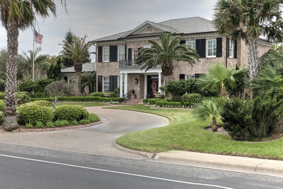 Brick residential house with green lawn illustrative of suburban construction